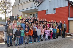 Das Bild zeigt Schülerinnen und Schüler und Lehrkräfte vor der Schule.
