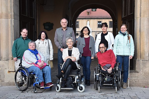 Das Bild zeigt eine Gruppe von Menschen mit verschiedenen Beeinträchtigungen vor dem Stadtschloss.